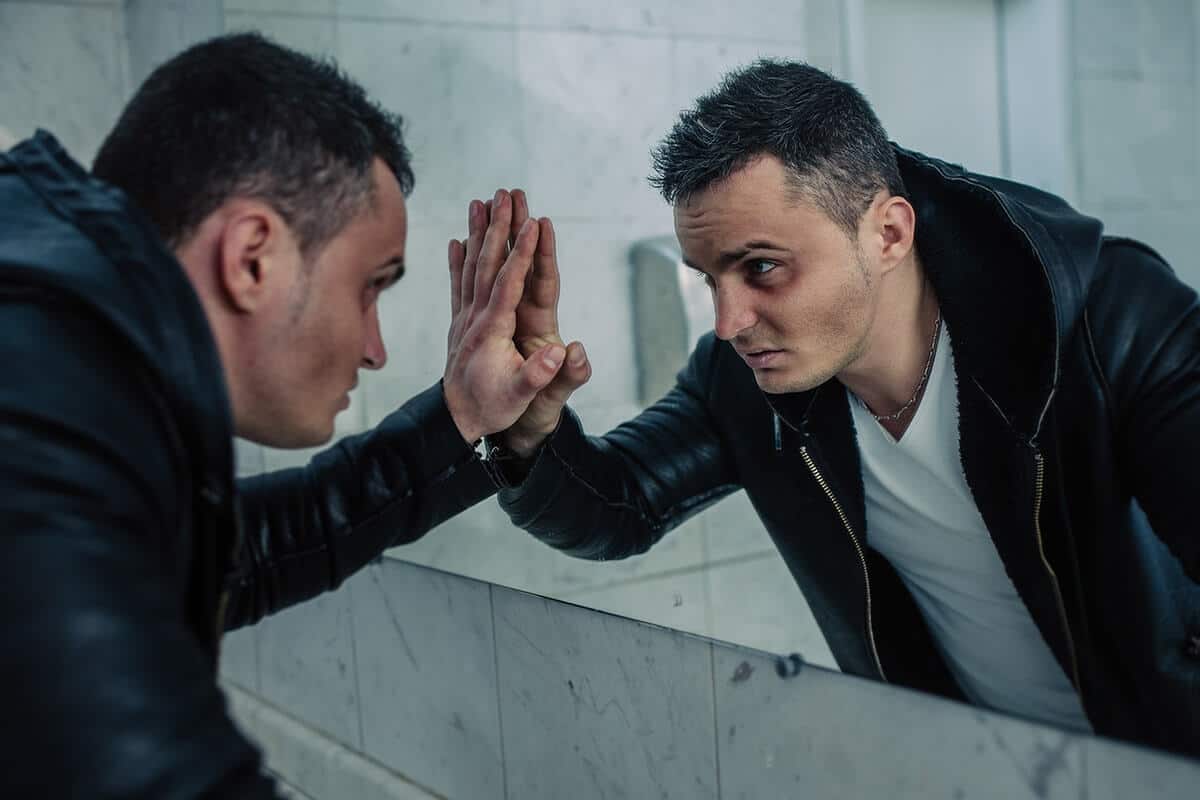 Man looks at himself in the mirror and contemplates the pros and cons of methadone treatment