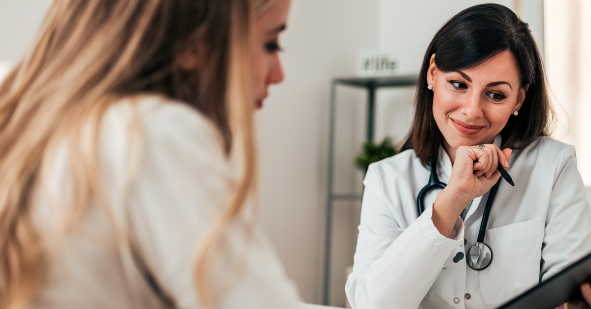 A brunette, woman doctor and a blonde, woman patient discuss a MAT treatment plan in a doctor's office.
