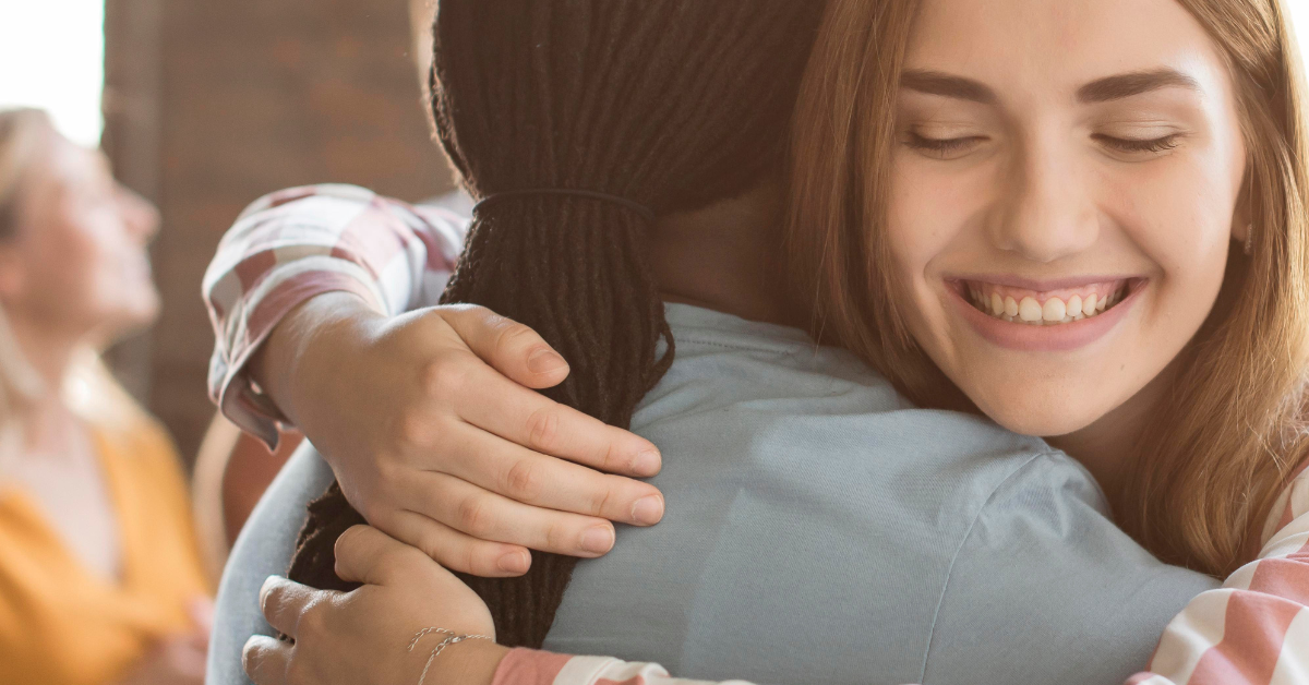 Two women embrace during a group therapy session during Mental Health Awareness Month.