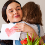 A mother in recovery embraces her child after receiving flowers and a card with a hand drawn heart.